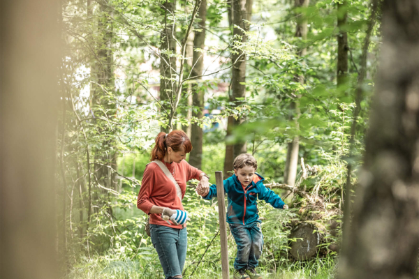 balancieren-parcour-im-wald-trixi-park-zittauer-gebirge Kind balanciert mit Hilfe auf dem Waldparcour im Trixi Park Zittauer Gebirge