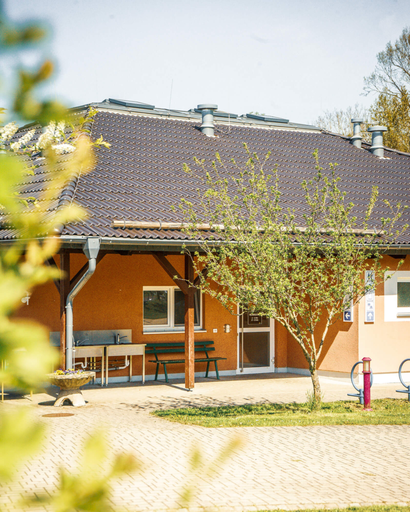 Eingang zum Sanitaergebaeude mit Waschplaetzen im Freien