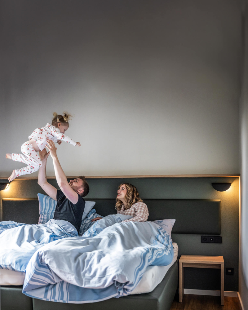 Familie am morgen, aufwachen im Doppelbett im Ferienhaus im Trixi Park