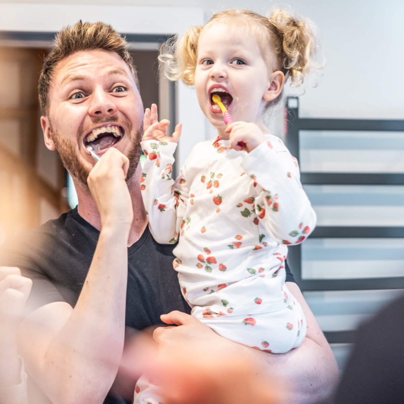 Vater mit Tochter im Badezimmer beim Zaehneputzen im Ferienhaus