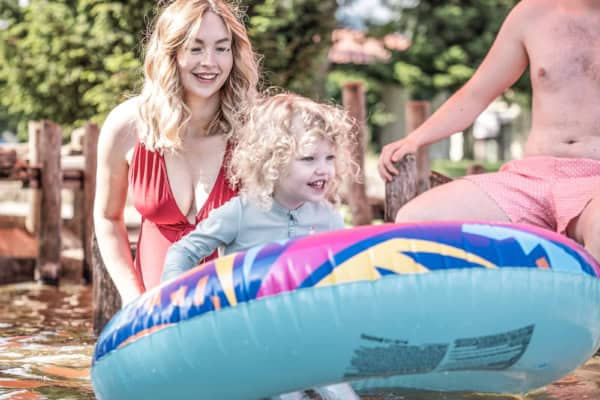 kind-mit-schwimmring-im-waldstrandbad-trixi-bad-grossschoenau Kind mit grossem Schwimmring im Wasser mit Eltern - Trixi Bad