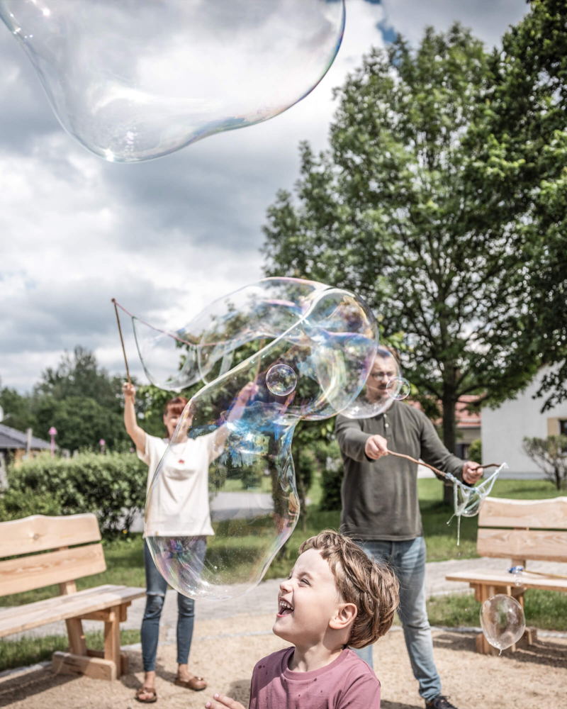 seifenblasen-animation-kidsclub-trixi-park-zittauer-gebirge Eltern lassen Seifenblasen steigen und Kind spielt mit ihnen