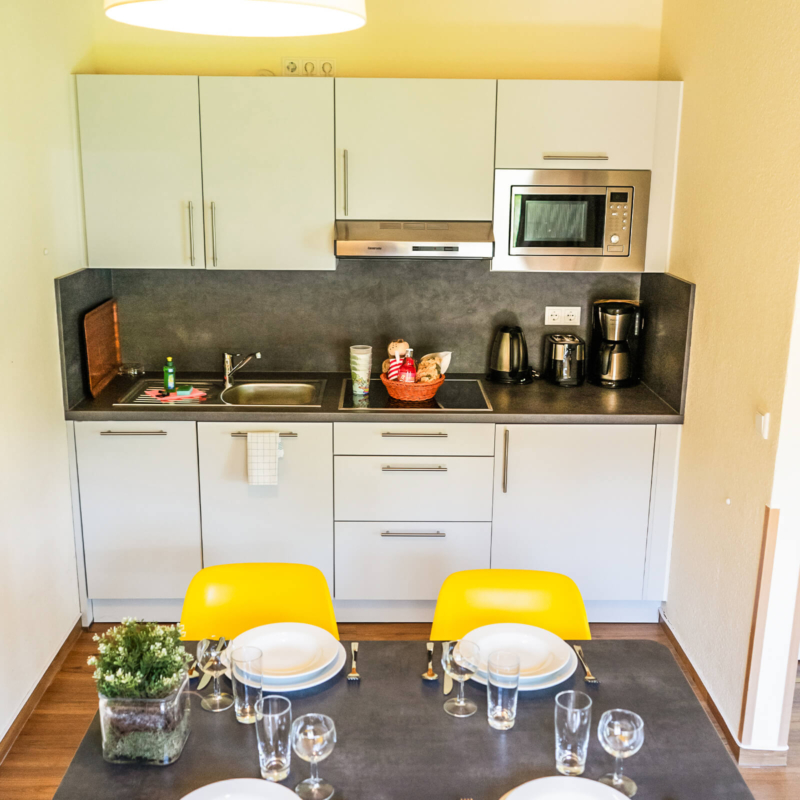 gedeckter Esstisch und Kuechenzeile im Ferienhaus